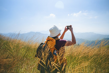 A female hiker taking photos on mobile phone over the mountains