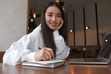 Young blogger working with laptop in cafe