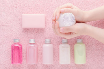 hands with a bottle and natural cosmetic, shampoo, lotion, shower gel and other products, above