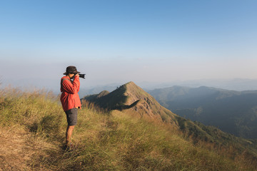Fototapeta premium Young male photographer taking photos over the mountain