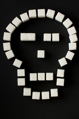scull shape with sugar cubes on black background