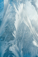 Ice pattern on glass, frosty ornament. Winter concept. Asbract blue winter background, frosty day. Vertical