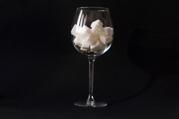 white sugar cubes in a wine glass on black background