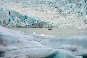People in little inflatable rubber boat close to Vatnajokull glacier in Fjallsarlon glacier lagoon...