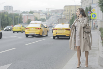 business lady stands road, cars, traffic, urban style, travel in the city, woman and cars