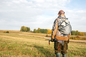 Hunter man in camouflage with a gun in the fall hunting season.