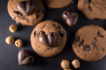 Chocolate heart for lovers lies on cookies on a table next to nuts