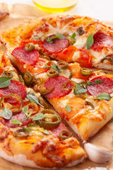 Homemade spicy pepperoni pizza and cooking ingredients. Pepperoni pizza on a white wooden table.