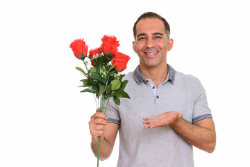 Mature happy Persian man holding red roses