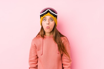 Young caucasian woman wearing a ski clothes isolated shrugs shoulders and open eyes confused.