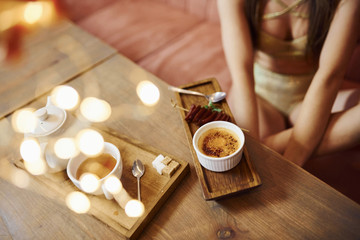 Sexy young woman lying down on the sofa near table with fresh food and drinks.