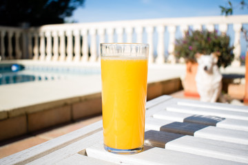 Freshly squeezed orange juice in the summer with views on swimming pool and the sea, glass of...