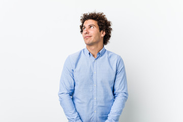 Young curly mature man wearing an elegant shirt dreaming of achieving goals and purposes
