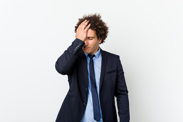 Young business curly man against white background forgetting something, slapping forehead with palm and closing eyes.