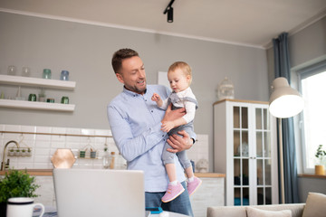 Fototapeta premium Man in a blue shirt standing and holding his daughter