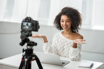 Naklejka premium selective focus of cheerful african american video blogger in braces gesturing near digital camera