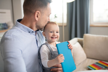 Fototapeta premium Man in a blue shirt kissing his baby girl