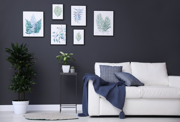Beautiful paintings of leaves on black wall in living room interior