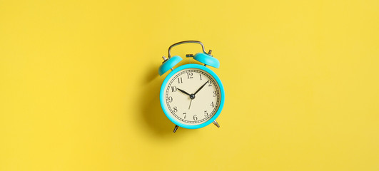 Fototapeta Turquoise vintage alarm clock on yellow background. Top view. Flat lay obraz