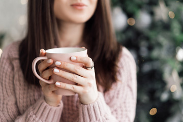Pink coffee mug in female hands. Woman drinking hot coffee
