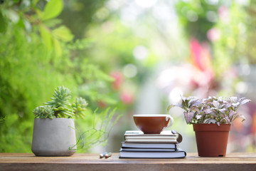 Brown coffee cup with notebooks and plants at outdoor