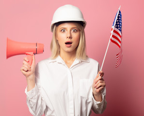 Woman in white shirt and helmet holds loudpeaker and USA flag