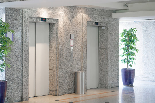 View Of Two Elevator Doors In Office Building. Wide Angle View Of Several Modern Elevators With Closed Doors. Elevators In The Modern Lobby.