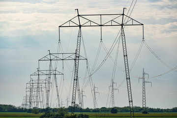 A number of high voltage electricity poles in the field. Shot below. Sky background graphic. - 317528631
