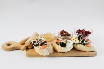 Delicious fresh bruschettas with eggs, salmon, olives and meat , traditional Italian cuisine, ingredients on white  table