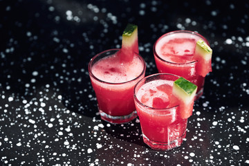 Summer cocktail with watermelon on black metal surface.