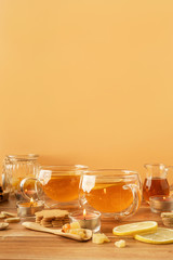 Two cups of tea with lemon, honey, ginger root ingredients and ginger biscuits on wooden table. Natural medicine concept. Mockup for your design. Close-up.
