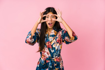 Young asian woman wearing a kimono pajamas keeping eyes opened to find a success opportunity.