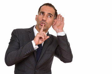 Mature handsome Persian businessman listening with finger on lips