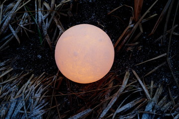 A full moon on the ground during the evening. Lunar model, moon-shaped lamp with moon craters