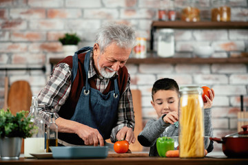 Grandpa and grandson in kitchen. Grandfather and his grandchild having fun while cooking. 