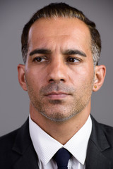 Face of mature handsome Persian businessman in suit thinking