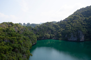 Scenic view on a lake surrounded by rocky mountain hills covered with trees on tropical island Ko Mae Ko within Ang Thong national marine park archipelago