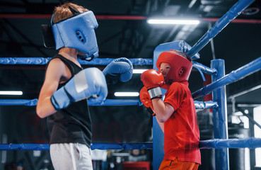 Two boys in protective equipment have sparring and fighting on the boxing ring