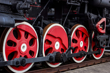 Old black and red retro steam locomotive wheels at the railway station. Vintage train staying on the railroad