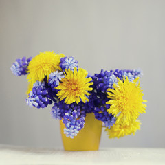 Spring bouquet of dandelions and muscari in a small vase.