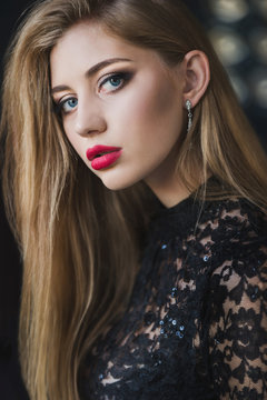 Portrait of beautiful young woman with long pale hair and makeup. red lipstick and evening lace dress