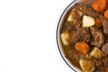 Irish beef stew with carrots and potatoes isolated on white background. Top view. Copy space	