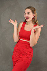Universal concept of a female portrait. Vertical photo of a pretty smiling girl with long hair and great makeup in a red dress with emotions in different poses.