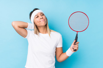 Young caucasian woman playing badminton isolated touching back of head, thinking and making a choice.