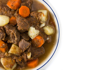 Irish beef stew with carrots and potatoes isolated on white background. Top view. Copy space	