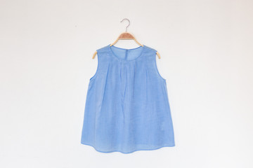 Blue colour blouse is clothes hanger on white background.