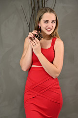 Universal concept female portrait on a gray background. Vertical photo of a pretty smiling girl with long hair and great makeup in a red dress with emotions in different poses.