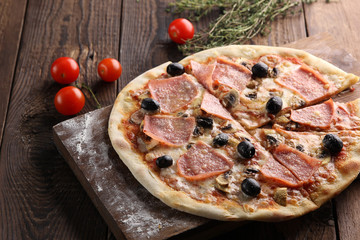 Italian cuisine. Pizza with ham and olives on a wooden background. Italian concept