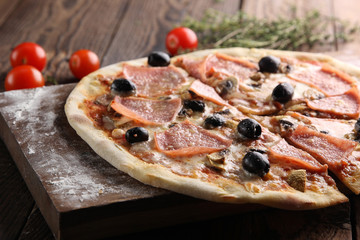 Italian cuisine. Pizza with ham and olives on a wooden background. Italian concept