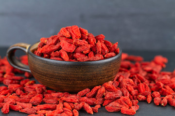 Goji berry cup many dried goji berries on grey slate. Selective focus